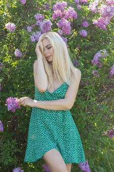 Fashionable girl model near a lilac bush. Spring flowers and beautiful blonde woman. Model appearance. Soft focus