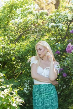 Fashionable girl model near a lilac bush. Spring flowers and beautiful blonde woman. Model appearance. Soft focus