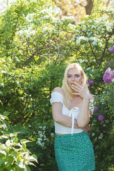 Fashionable girl model near a lilac bush. Spring flowers and beautiful blonde woman. Model appearance. Soft focus