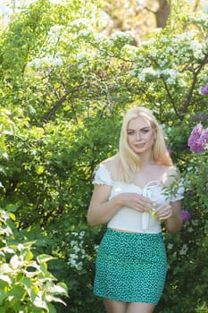 Fashionable girl model near a lilac bush. Spring flowers and beautiful blonde woman. Model appearance. Soft focus