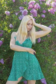 Fashionable girl model near a lilac bush. Spring flowers and beautiful blonde woman. Model appearance. Soft focus