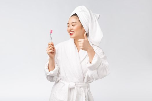 Asian happy woman with toothbrush in bathrobe morning mood.