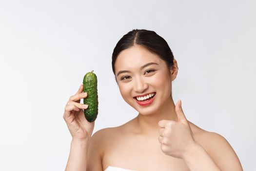 Asian young woman over isolated background holding cucumber