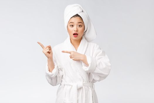 Beauty portrait of young woman showing and pointing finger to empty copy space, asian beauty in bathrobe