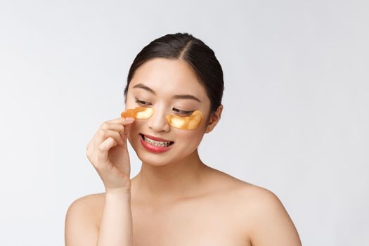 Asian beauty teenager woman care her skin with gold eye masks patches under eyes.