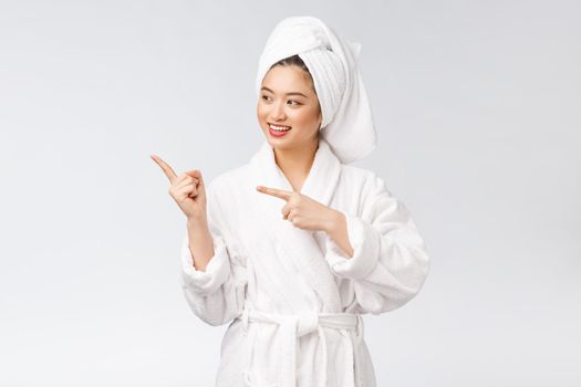 Beauty portrait of young woman showing and pointing finger to empty copy space, asian beauty in bathrobe