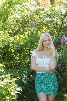 Fashionable girl model near a lilac bush. Spring flowers and beautiful blonde woman. Model appearance. Soft focus