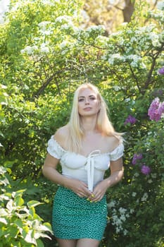 Fashionable girl model near a lilac bush. Spring flowers and beautiful blonde woman. Model appearance. Soft focus