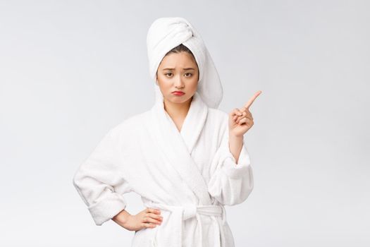 Beauty portrait of young woman showing and pointing finger to empty copy space, asian beauty in bathrobe