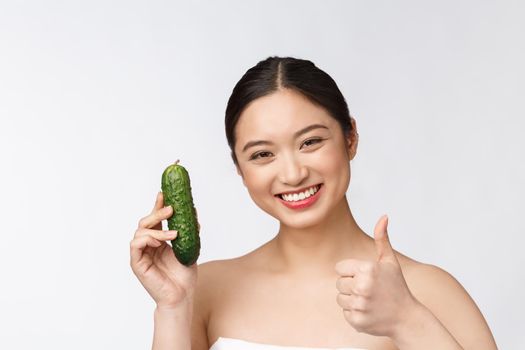 Asian young woman over isolated background holding cucumber