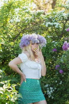Beautiful woman in lilac Garden. Girl with lilac wreath in springtime. Gardening. Soft focus