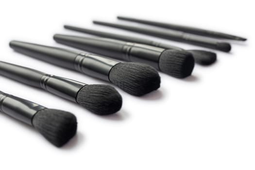 Closeup of black makeup brushes isolated on white background. Blurred background
