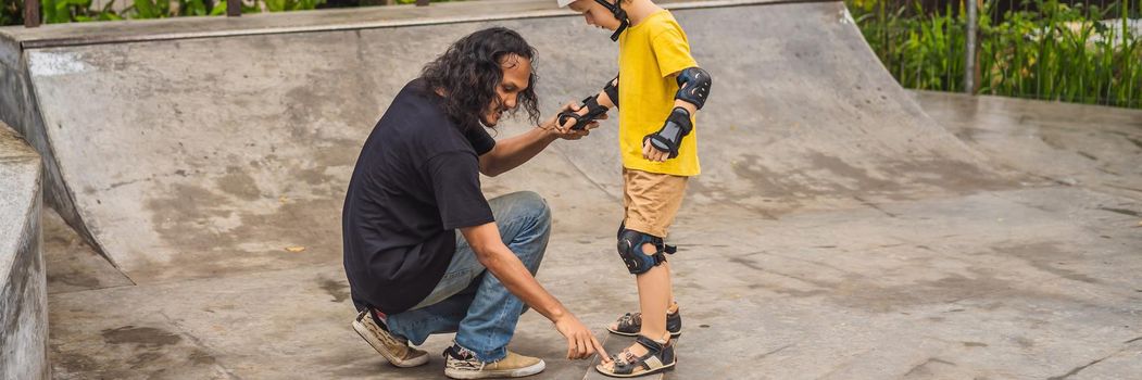 Athletic boy learns to skateboard with a trainer in a skate park. Children education, sports. BANNER, LONG FORMAT