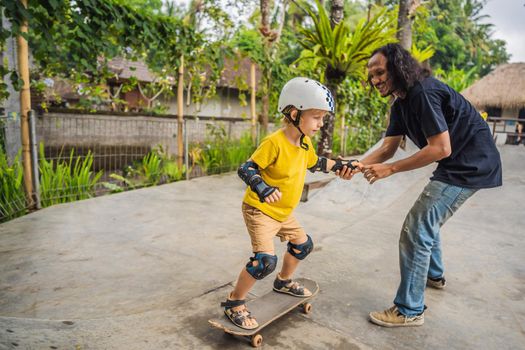 Athletic boy learns to skateboard with asian trainer in a skate park. Children education, sports. Race diversity.