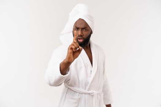 Black guy wearing a bathrobe pointing finger with surprise and happy emotion. Isolated over whtie background