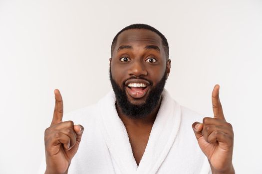 Black guy wearing a bathrobe pointing finger with surprise and happy emotion. Isolated over whtie background