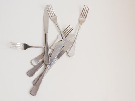 Food background - high angle view of four forks and knives scattered on white table with copy space to right