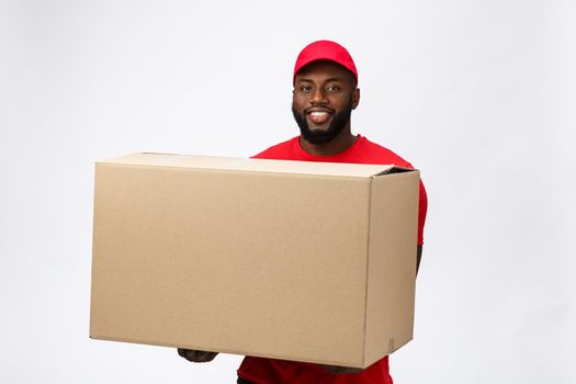 Delivery Concept - Handsome African American delivery man carrying package box. Isolated on Grey studio Background. Copy Space.