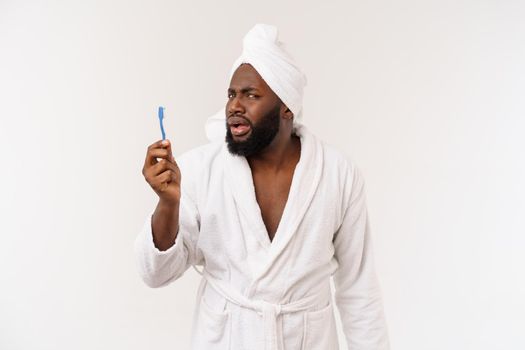 portrait of a happy young dark-anm brushing his teeth with black toothpaste on a white background