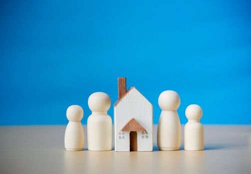 Four wooden figures people standing nearby of tiny wooden house. Concept for family, loan, property ladder, financial, mortgage, real estate investment, taxes and bonus.