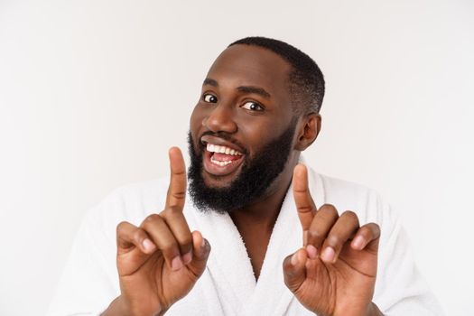 Black guy wearing a bathrobe pointing finger with surprise and happy emotion. Isolated over whtie background