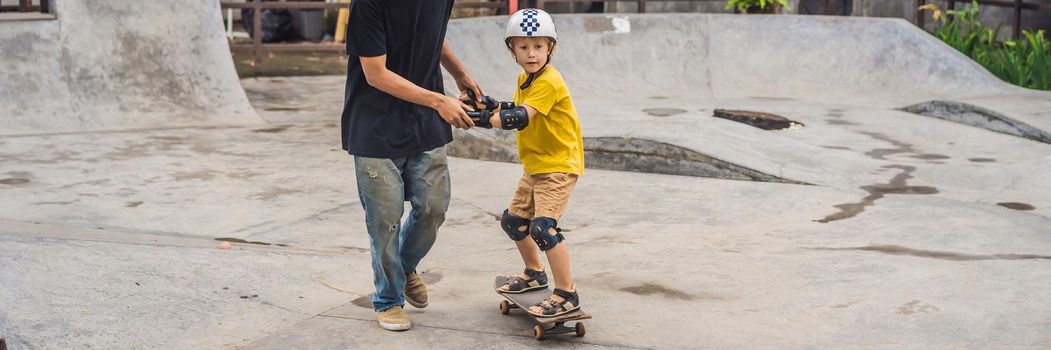 Athletic boy learns to skateboard with asian trainer in a skate park. Children education, sports. Race diversity. BANNER, LONG FORMAT