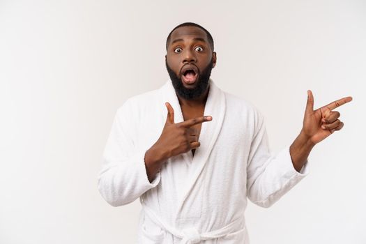 Black guy wearing a bathrobe pointing finger with surprise and happy emotion. Isolated over whtie background