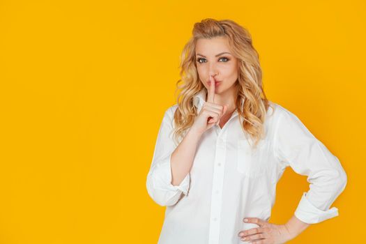 A serious woman silently looks at the camera, pressing her index finger to her lips, frowning disapprovingly, scolding for being too loud. says: shut up, shut up, shh quietly, please.