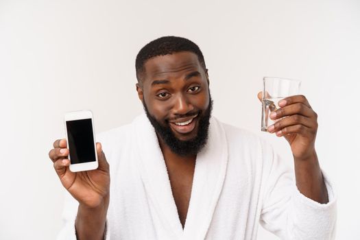 Thirsty young african man holding glass drinking water for body health isolated on white studio background.