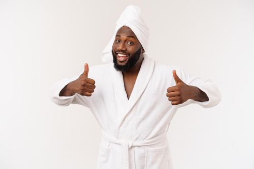 Black guy wearing a bathrobe showing thumb up with surprise and happy emotion. Isolated over whtie background