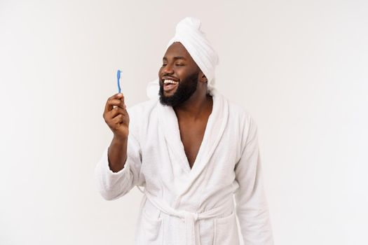 portrait of a happy young dark-anm brushing his teeth with black toothpaste on a white background