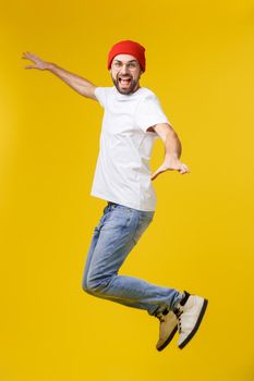 young casual man jumping for joy on yellow gold background.