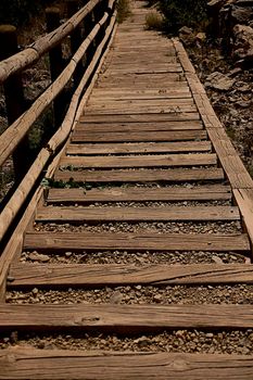 Stairs with wooden steps going down the mountain. Rustic, handcrafted, rocks front view, downhill, wooden railing