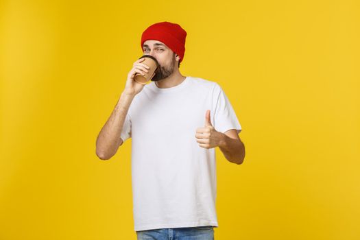 Man on isolated vibrant yellow color taking a coffee in takeaway paper cup and smiling because he will start the day well