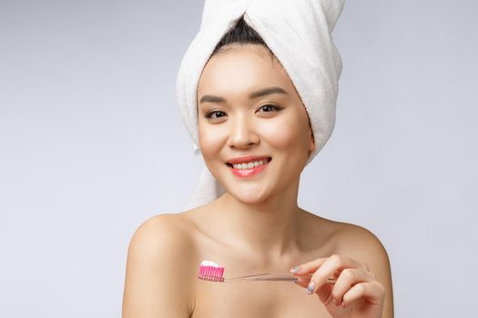 Beautiful young woman on white isolated background holds a toothbrush, Asian.