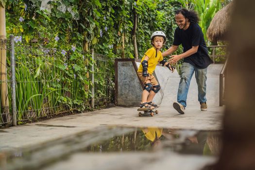 Athletic boy learns to skateboard with asian trainer in a skate park. Children education, sports. Race diversity.