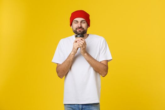 Man on isolated vibrant yellow color taking a coffee in takeaway paper cup and smiling because he will start the day well