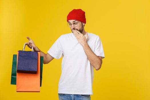 Bearded man with shopping bags with happy feeling isolated on yellow bacground.