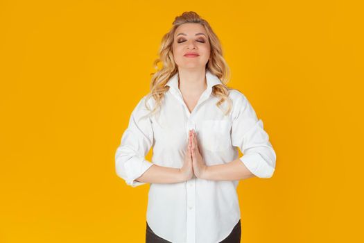 A woman in a white shirt with her arms folded near her chest, when she makes a wish, closes her eyes and asks to pray with her head raised to the sky, waiting for good news.