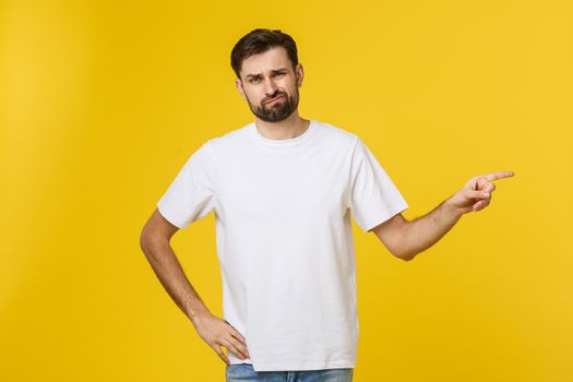 Handsome man over isolated yellow wall frustrated and pointing to the front