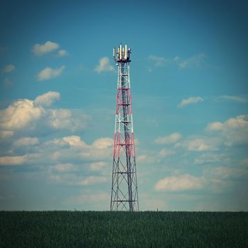 Transmitter for gsm signal of mobile phones in the field. In the background blue sky with clouds. Concept for modern technology and industry - Telecommunication Tower.
