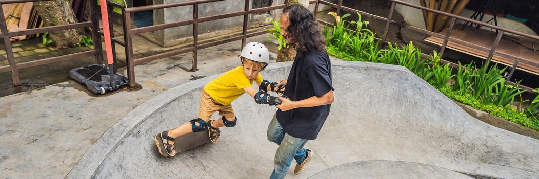 Athletic boy learns to skateboard with a trainer in a skate park. Children education, sports. BANNER, LONG FORMAT