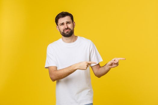 Handsome man over isolated yellow wall frustrated and pointing to the front