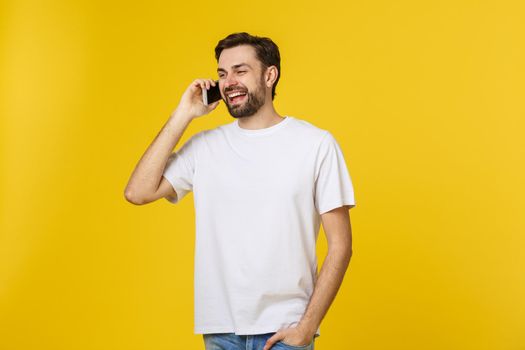 young casual man talking on the phone isolated on yellow background.