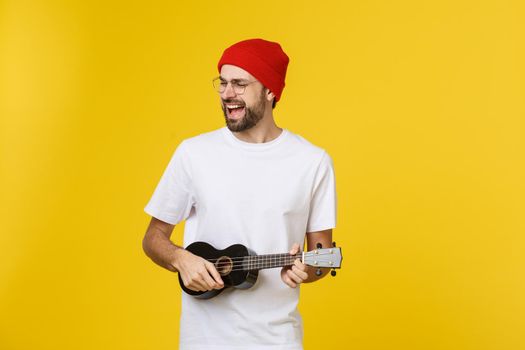 close-up of funny young man playing a guitar. isolated on yellow gold background.