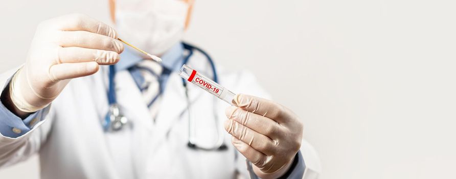 Test for coronavirus Covid-19. Male doctor or nurse doing nasal swab laboratory analysis in a hospital laboratory. A medical technologist holds a COVID-19 smear kit by wearing protective gloves.
