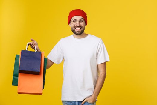 Bearded man with shopping bags with happy feeling isolated on yellow bacground.