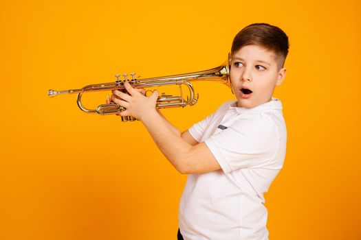 The boy overhears through the pipe. I want to hear everything. Handsome curious boy in a white shirt with a curious expression on his face while spying, eavesdropping, holding a pipe near his ear