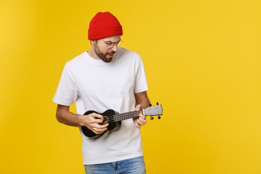 Young handsome guitar player. Studio shot on yellow background