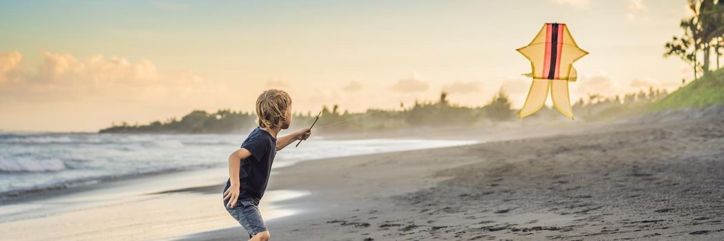 Happy young boy flying kite on the beach at sunset. BANNER, LONG FORMAT
